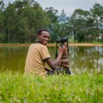 1. Hillary photographing wildlife, alt: "Local guide and photographer Hillary on a Uganda photo safari"